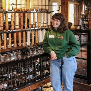 Allison Meyette stands in front of spinning machine at Slater Mill