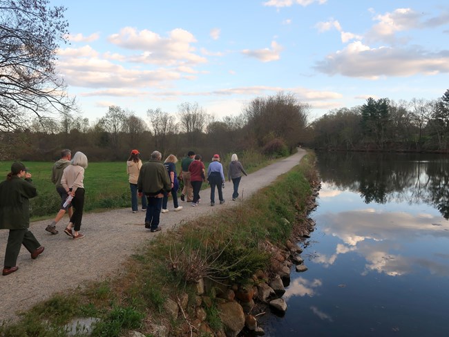 Group of people walking along stone path along canal