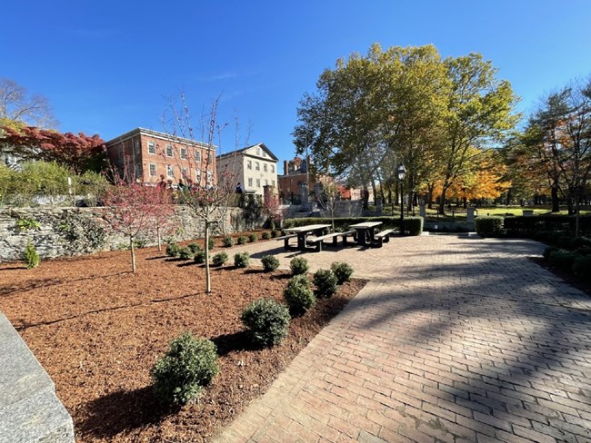 Brick picnic area with new trees planted and red mulch