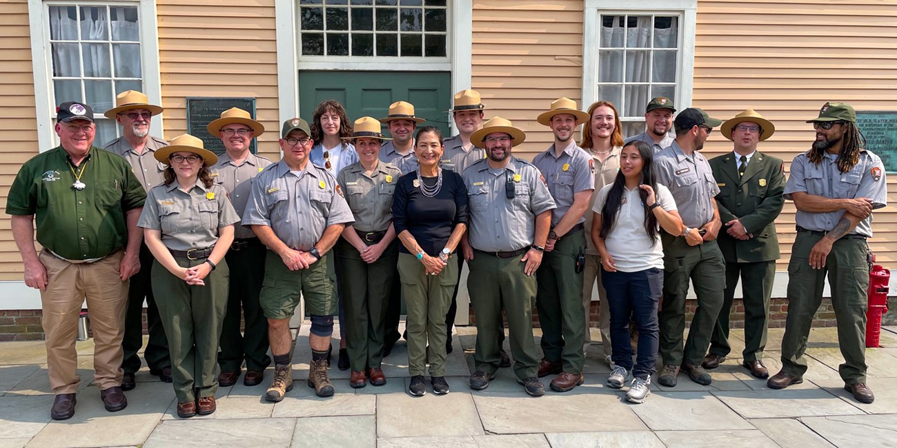 lt= Secretary Haaland standing with park rangers