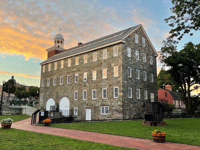 A stone mill with sunlight reflecting off the windows