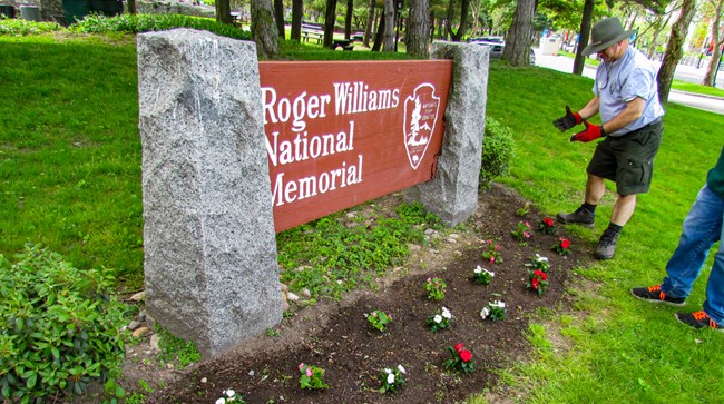 Park staff planting flowers in front of park entrance sign