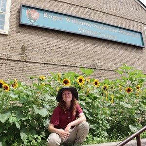 lt= Intern Tatum standing next to sunflowers