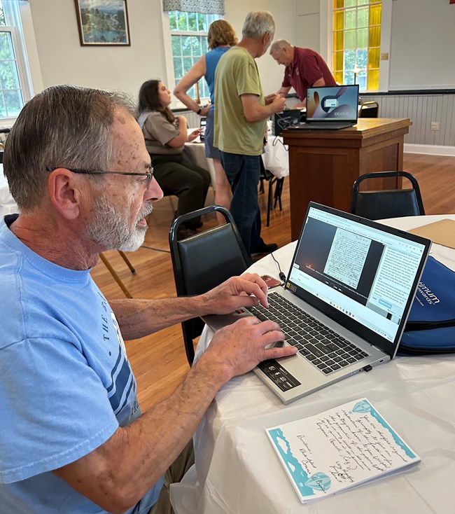 Transcription Event Man sits at desk with computer and pad of paper