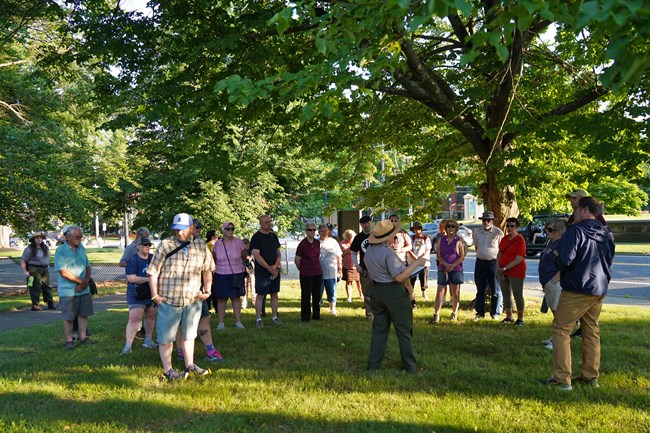 Walkabout picture_Allison Whitinsville Group of people stand around ranger. All standing underneath a tree