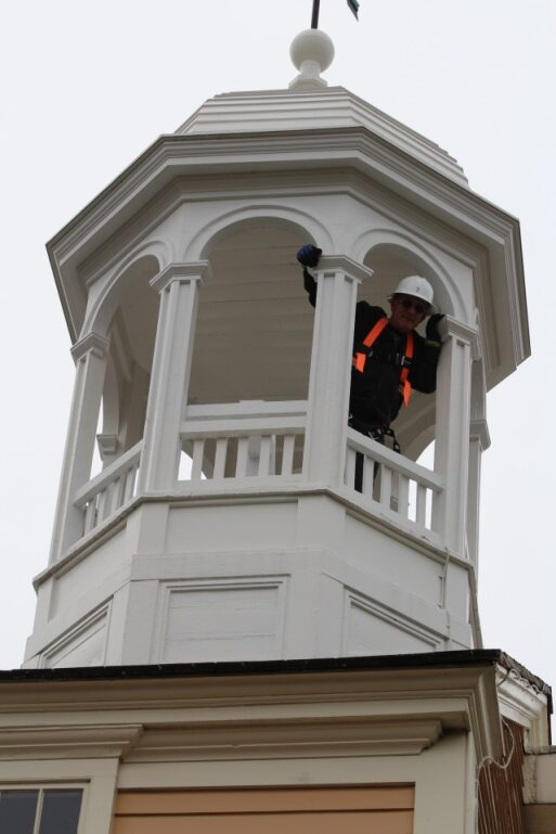 bell tower repari Man with safety equipment waves from Bell Tower cupola