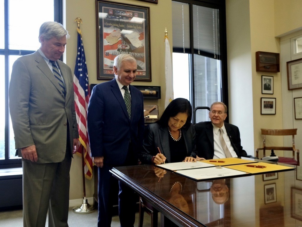 secretary-haaland-signs-boundary-establishment-blackstone-river-valley-national-historical-park Secretary Haaland signing a document at a desk with members of the Rhode Island congressional delegation.