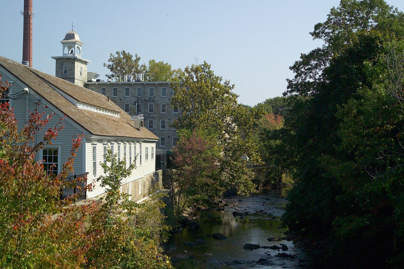 Branch river with stone mill and wooden building on left bank of the river
