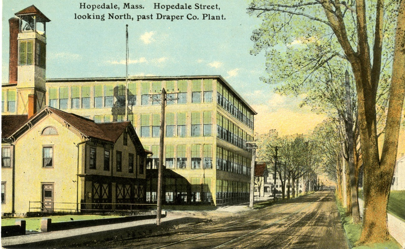 Postcard image of Hopedale mill. Mill on the left side of the image with street running through the center of the image