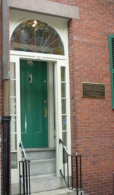 Brick building with white glass exterior door frame and green door.