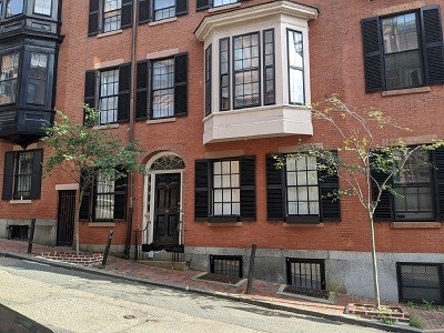 3 story brick townhouse with black window trimmings and a white bay window.