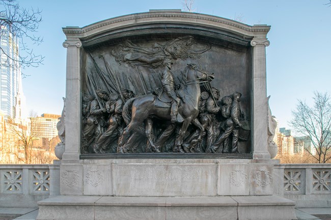 frontal view of the MA 54th Memorial, a bronze sculpture surrounded of soldiers marching