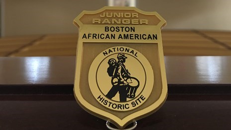 A single Boston African American National Historic Site Junior Ranger badge placed on a railing.