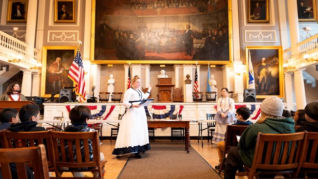 Rangers dressed in late 1800s outfits in the Great Hall of Faneuil Hall.