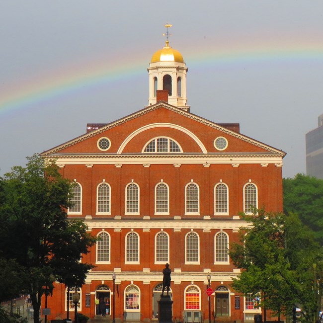 Faneuil Hall with a rainbow in the background.