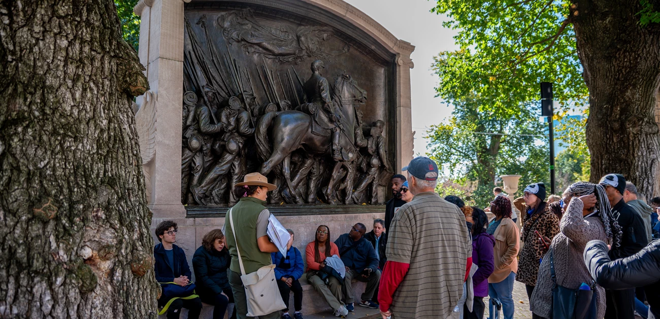 Ranger at Shaw Memorial A ranger faces a crowd while standing in front of a large monument