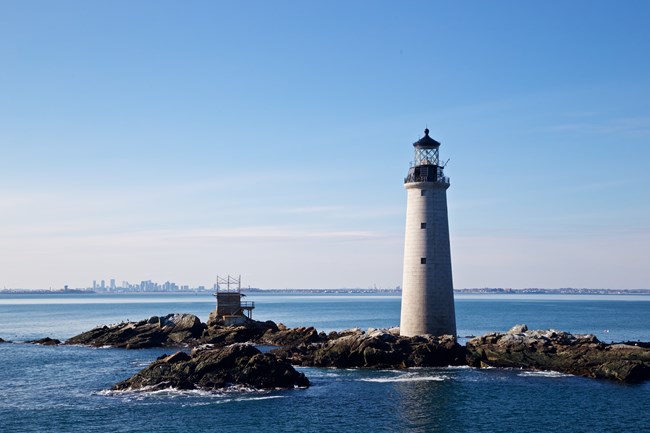 Boston Light. A white lighthouse, with a black top, on a small island.
