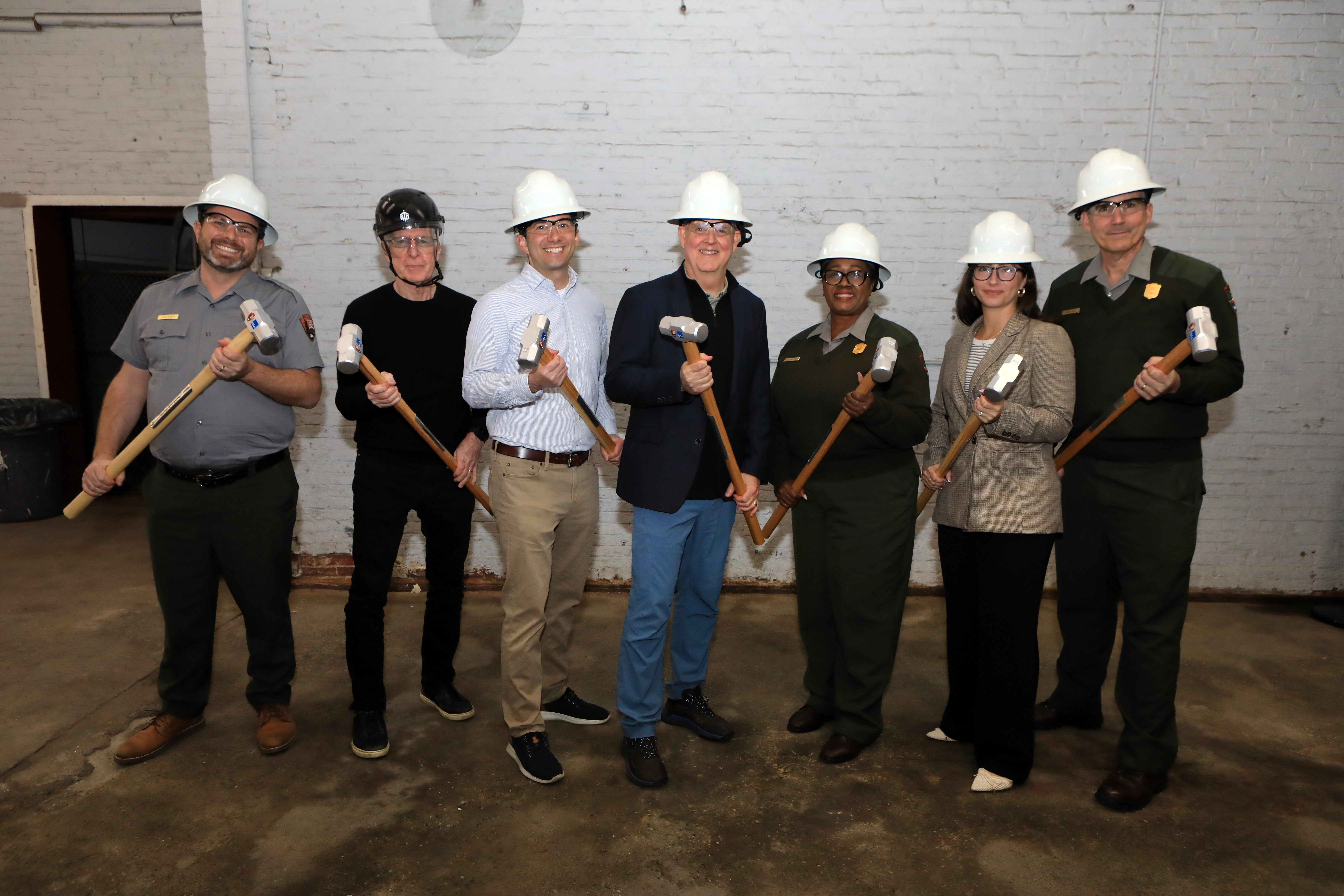 Group photo of people wearing hardhats and holding mallets. Some are in NPS uniform, and others wear suits.