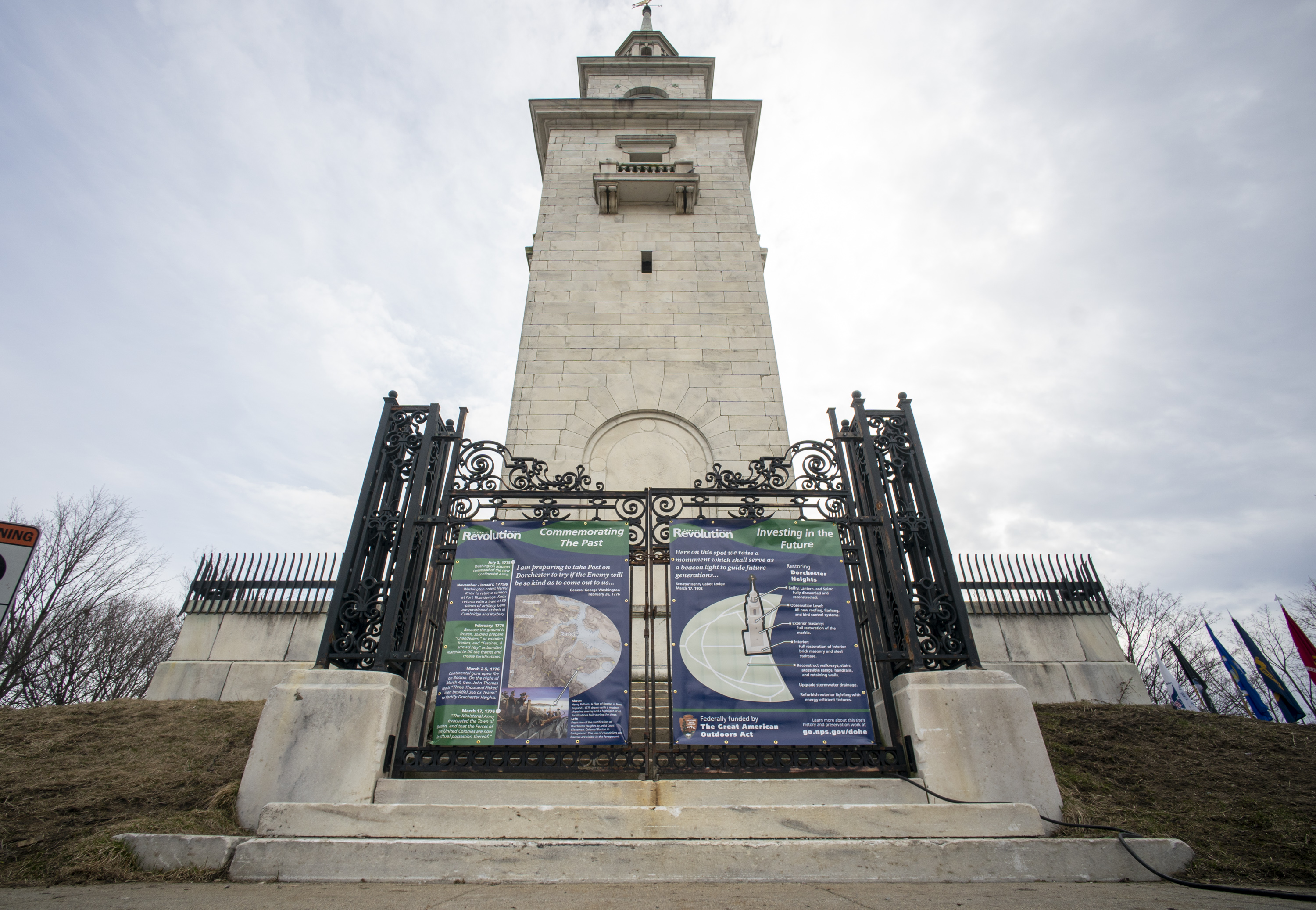 Dorchester Heights Monument with gates closed and vinyl exhibit on the history and restoration project on doors.