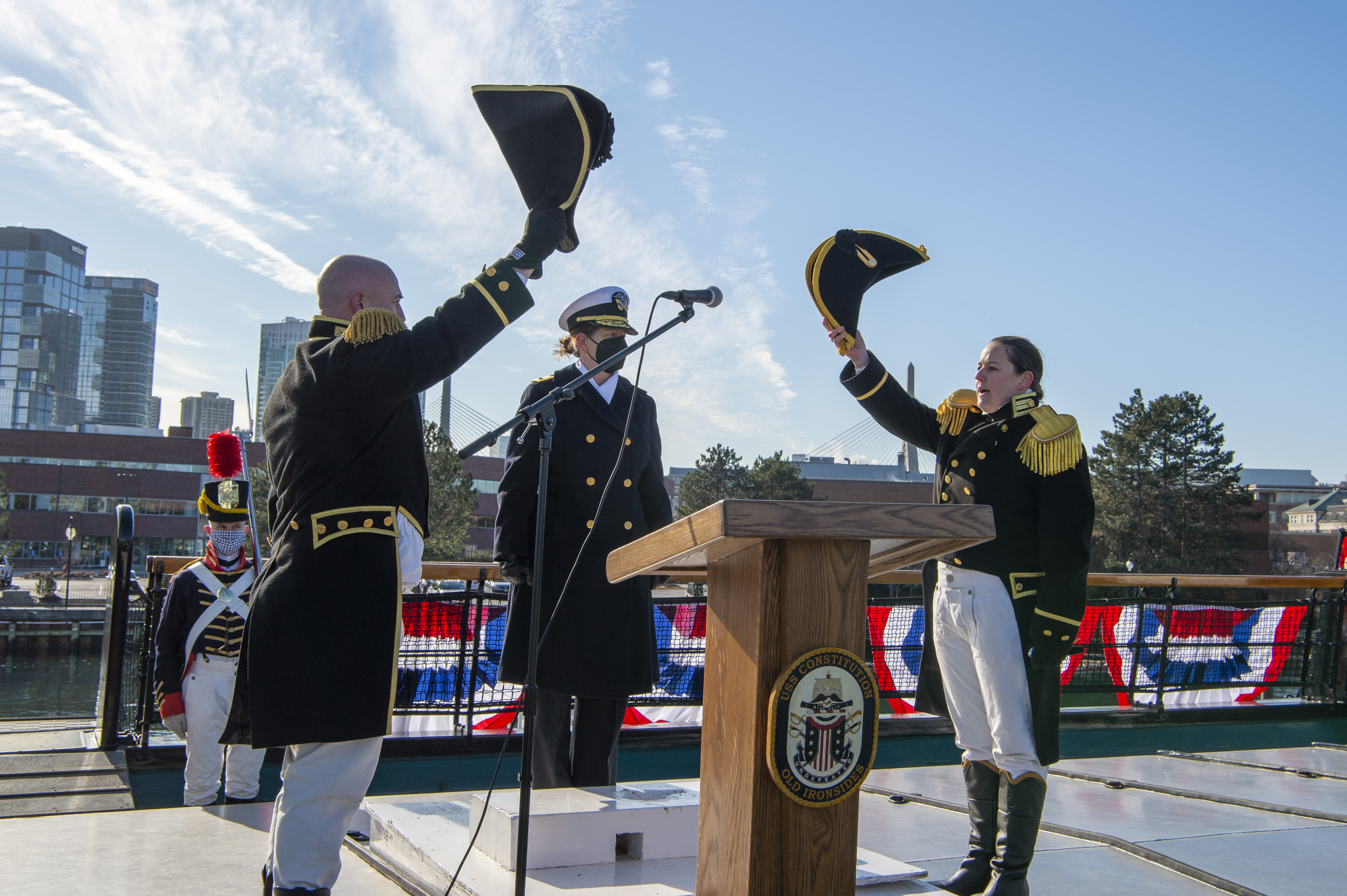 two commanders in 19th cen. dress uniform standing across from each other and raising their hats in salute.