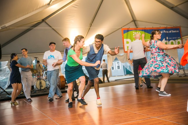 A couple in center dancing to music, other dancers are in the periphery.