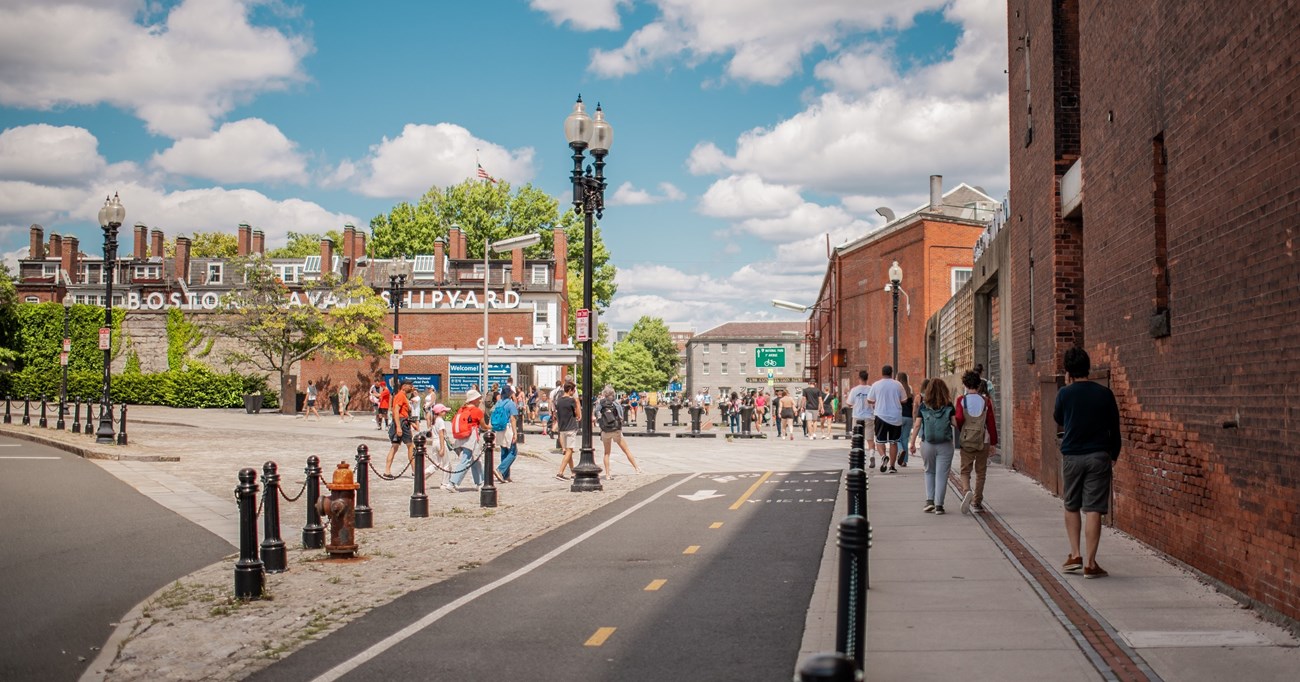 Gate 1 entrance to the Charlestown Navy Yard with people walking along the Freedom Trail through the entry.