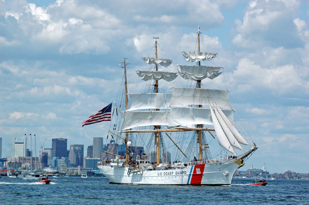 Tall ship with sails and white hull sails in Boston Harbor