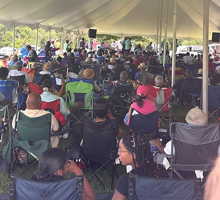 A group of seated spectators, face the stage preparing to listen to a musical group.