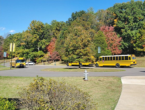 Yellow school buses parked in front of the Booker T. Washington Visitor Center parking lot.