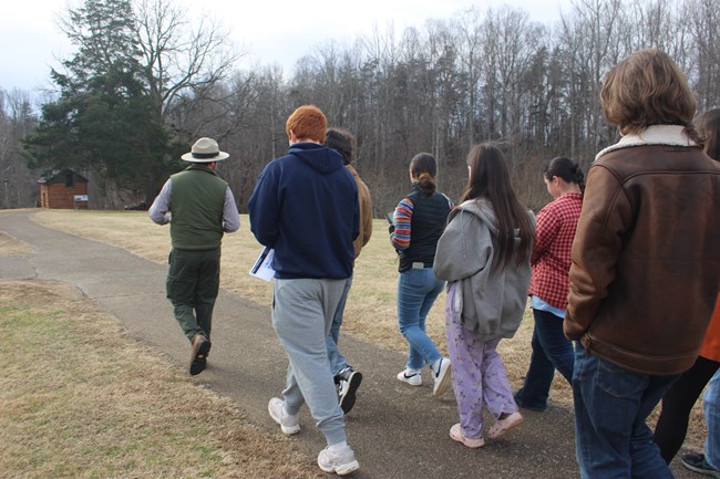 A park ranger leads a group of visitors to the reconstructed Kitchen Cabin during an interpretive tour.