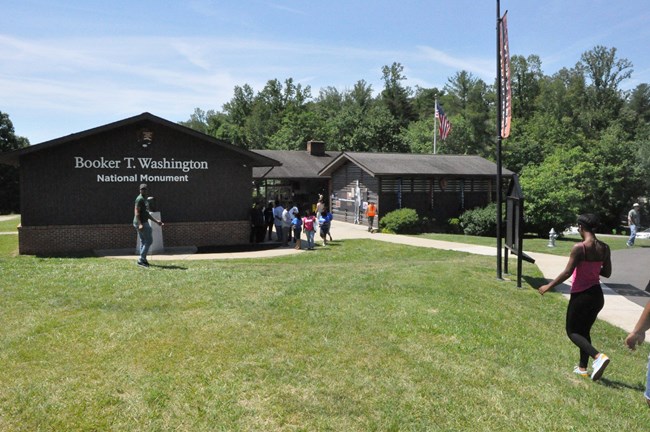 A group of visitors enter and leave a one-story brick structure.