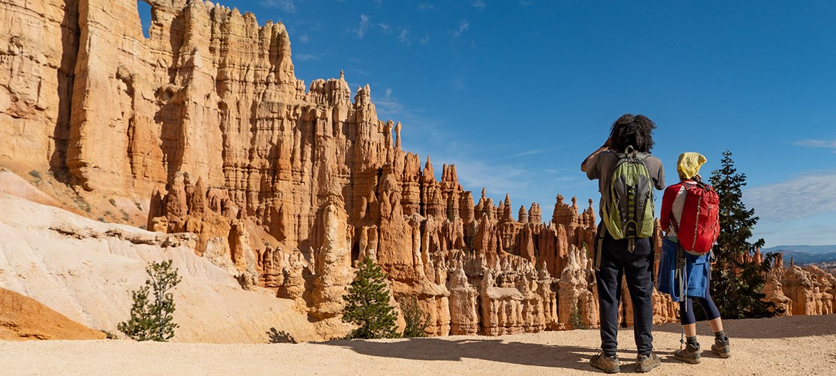 Two people along a trail near red rock spires