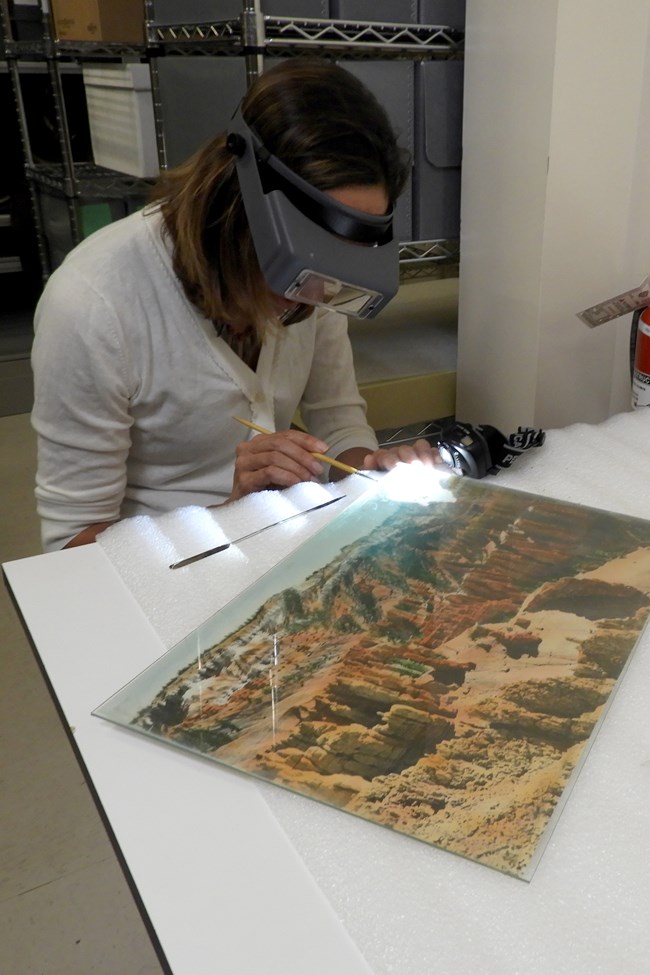 A color photograph of an archivist touching up a historic photograph