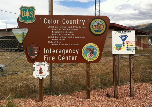 A sign for the Color Country Interagency Fire Center showing cooperating agency logos and a fire danger sign