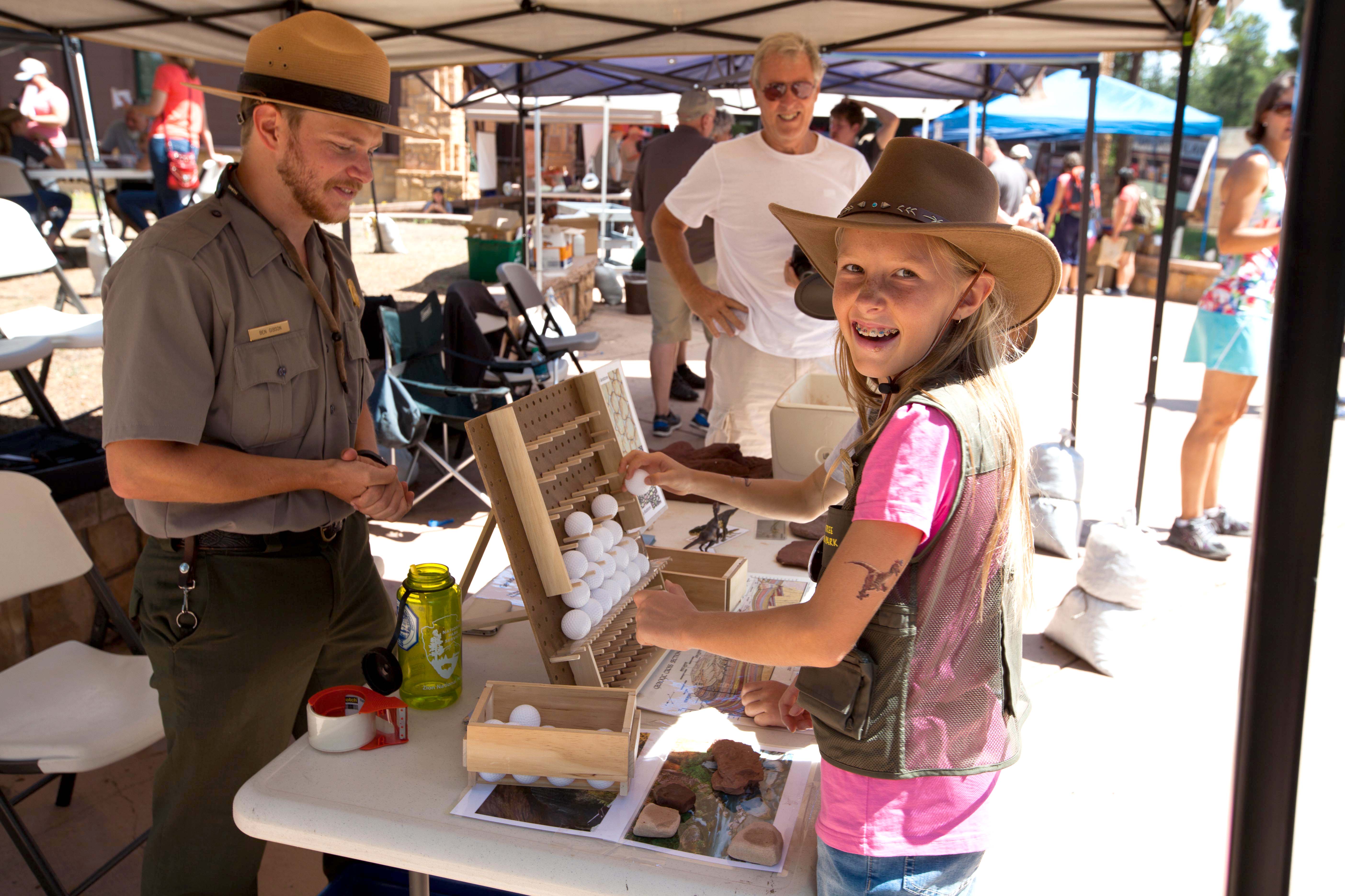 A young woman and a park ranger stand at an activity booth.