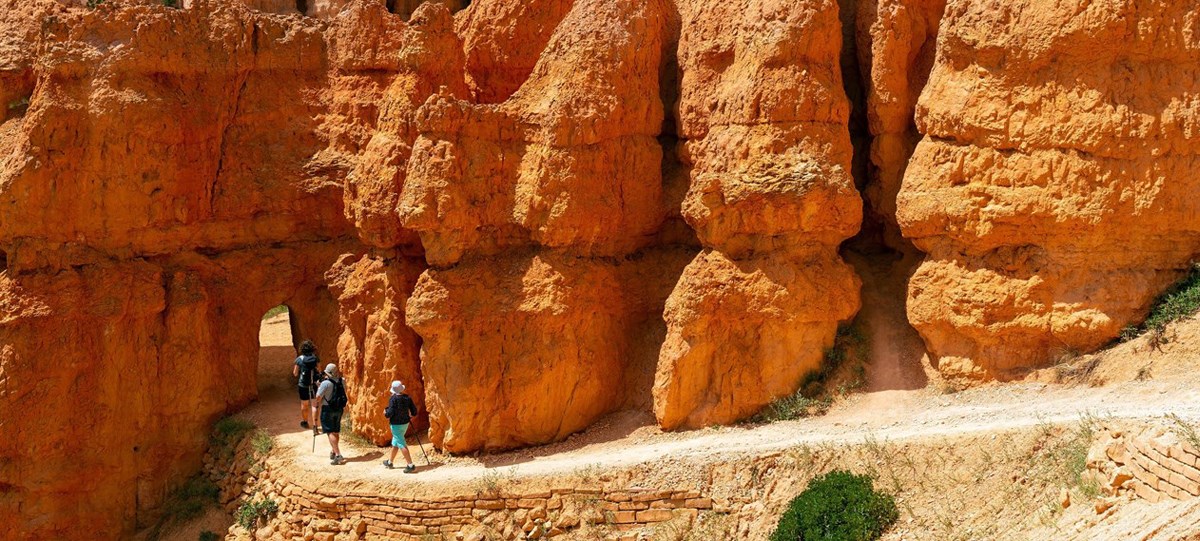 Hikers approach an archway on a hike