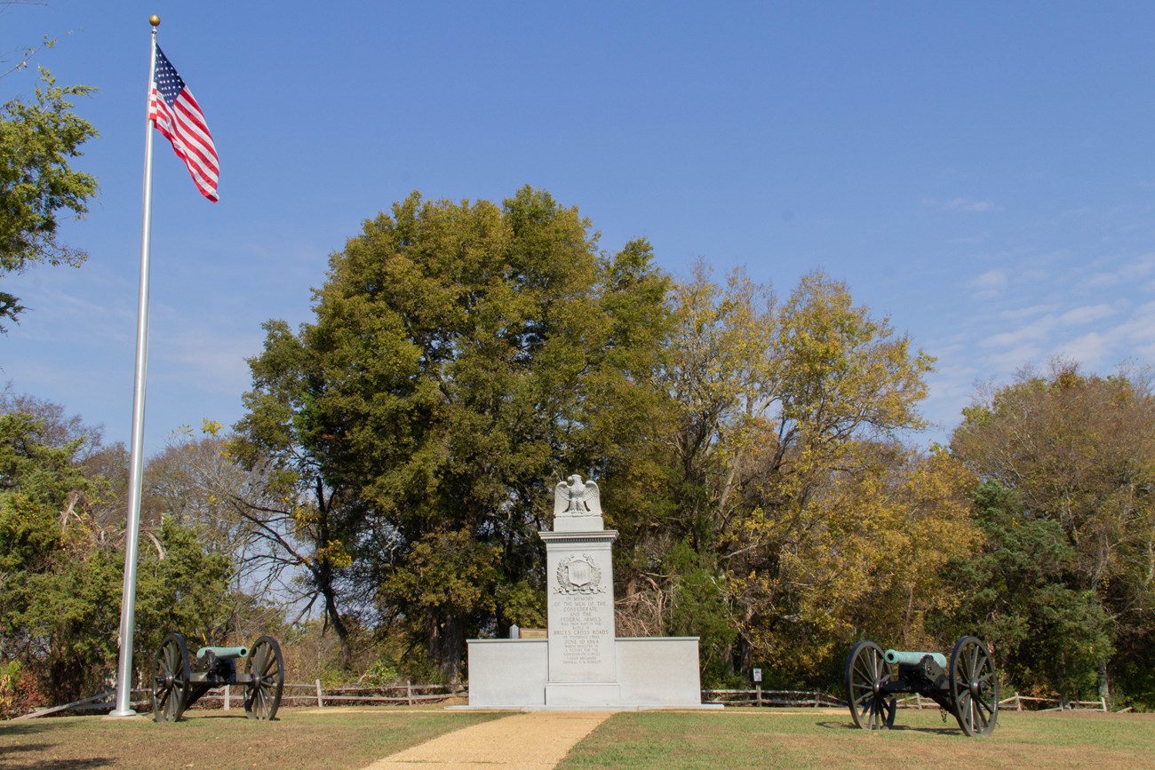 A stone monument, two Civil War-era canons, and an American flag flying.
