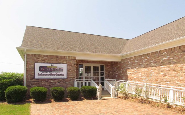 Brick building with five shrubs in front, and Mississippi's Final Stands logo on side of building