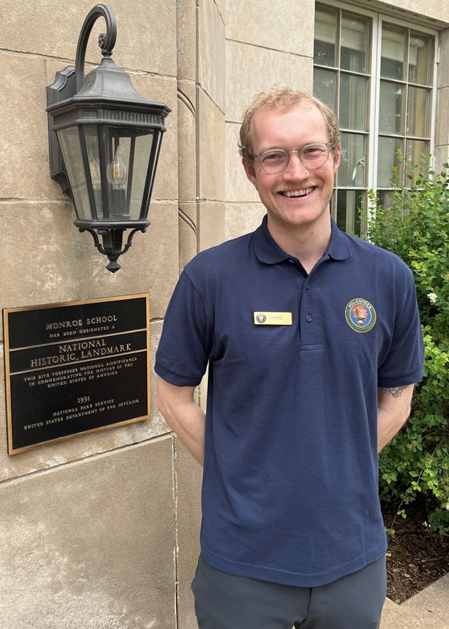 Volunteer Chris Dolphin stands beside the entrance of Brown v. Board of Education National Historical Park.