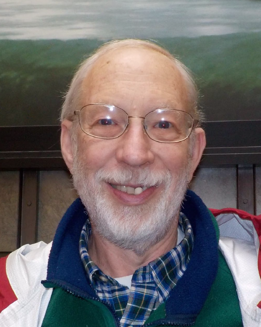 DavidGiven Older white man with white thin hair and beard wearing glasses smiles at the camera