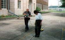 Image of man and woman pulling ground penetrating radar unit across concrete sidewalk.