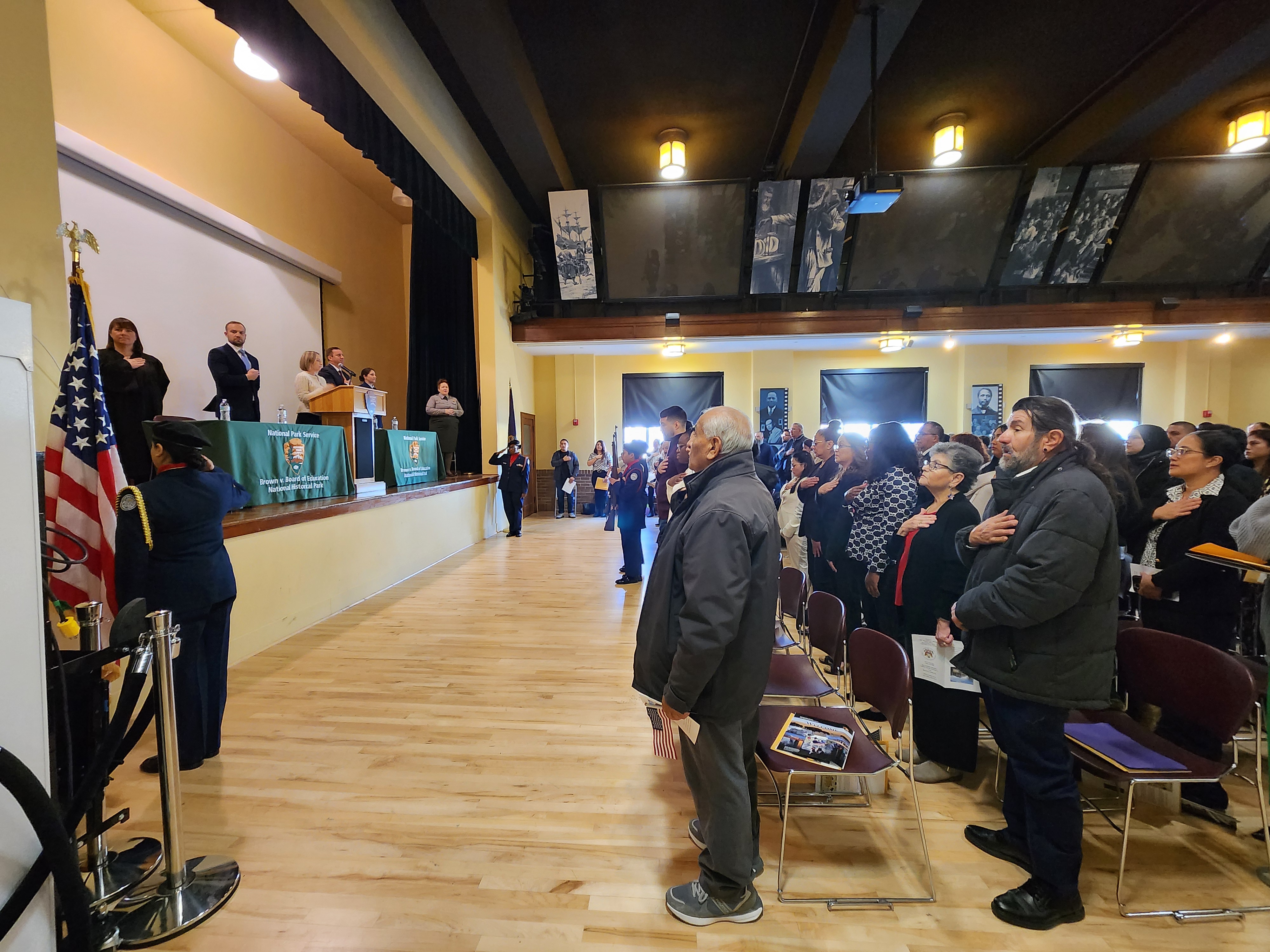 A crowd stands in an auditorium for the national anthem.