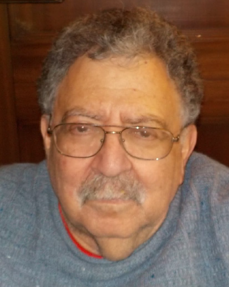 Headshot of an older black man with short white and black hair, metal rimmed glasses and a gray sweater.