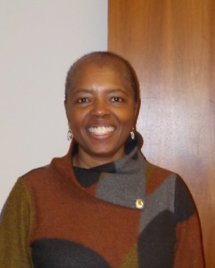SändraWashington portrait of an older black woman with short black hair smiling for the camera while wearing a brown grey and black patterned shirt
