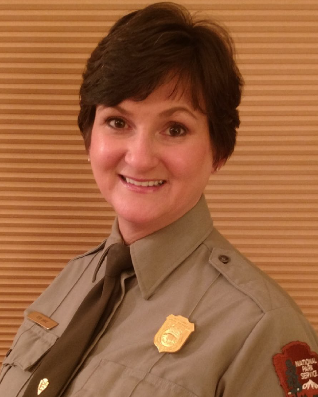 TeriGage A white female park ranger with medium length brown hair wearing her green and grey service uniform