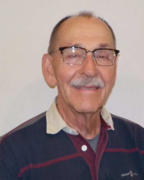 WarrenBielenberg Headshot of a balding older white man with short brown hair, brown glasses, and a white beared smiling at the camera wearing a navy blue polo with maroon stripes