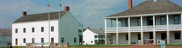 Entrance to Fort Scott National Historic Site: two buildings in the foreground, one with a wraparound porch. More buildings in the background.