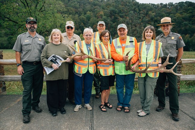 A group of volunteers and rangers pose together while holding elk antlers.