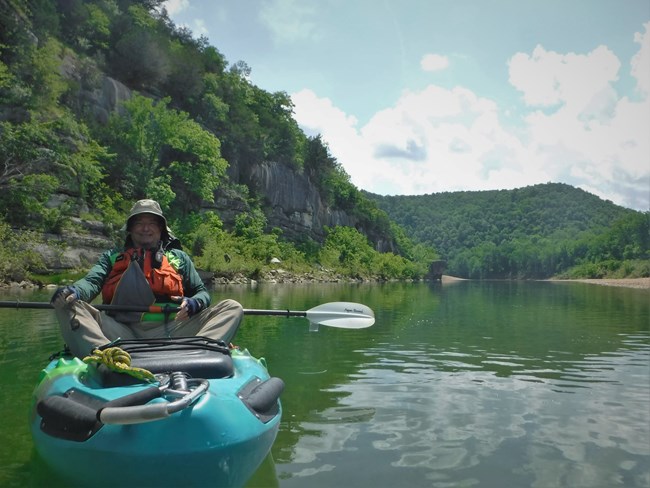 A paddler in a blue kayak smiles at us