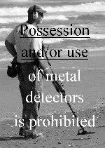 black & white photo of man using metal detector on the beach